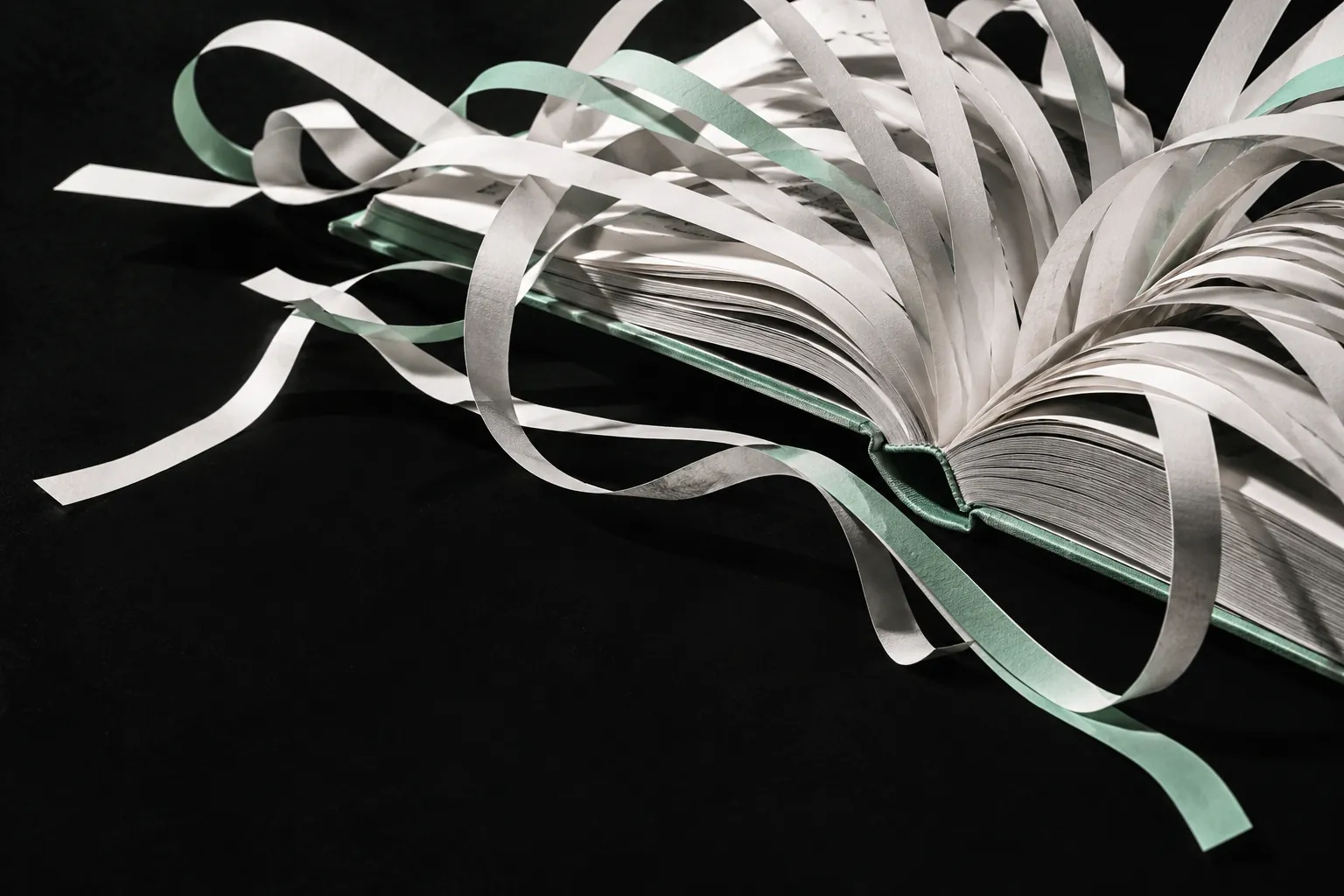 Conceptual illustration of book pages unfurling into paper ribbons, with a mint accent.